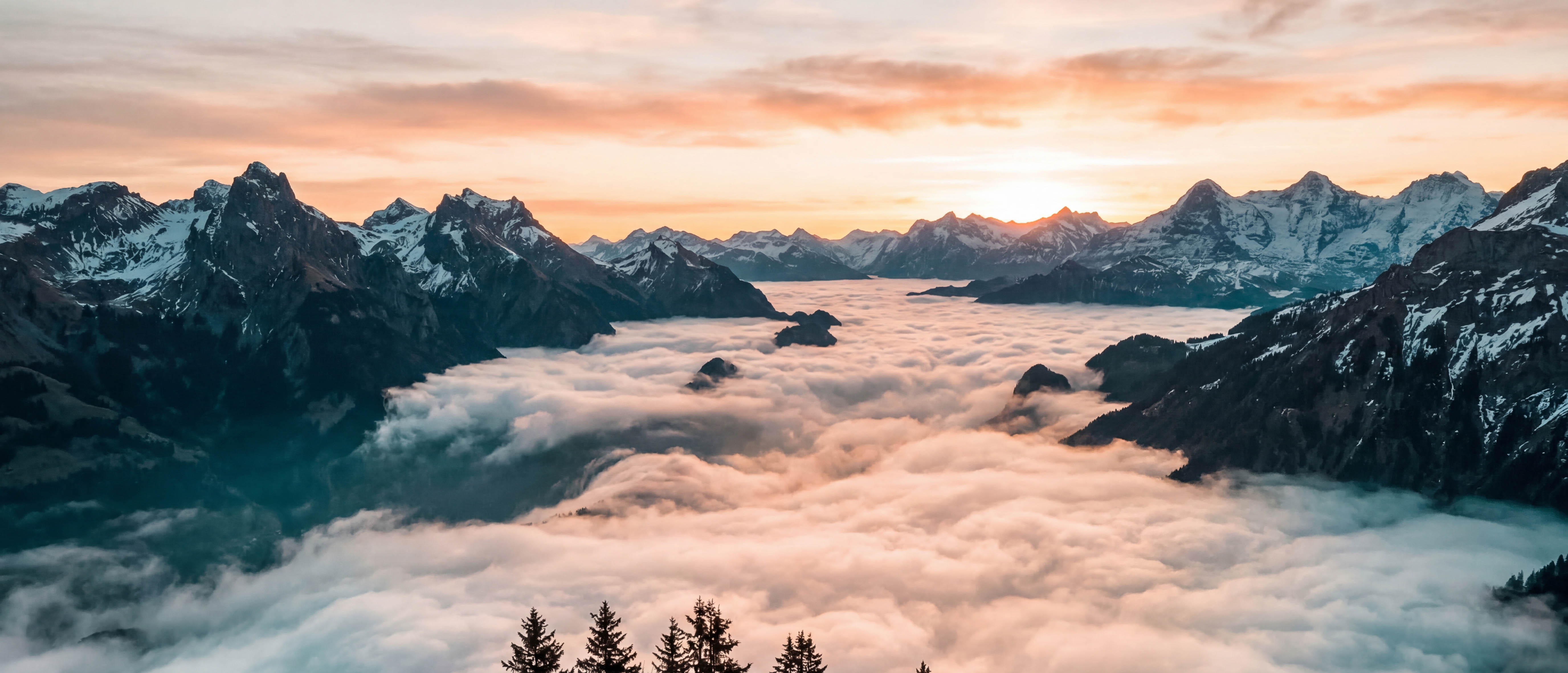 Morning fog filling an alpine valley at sunrise